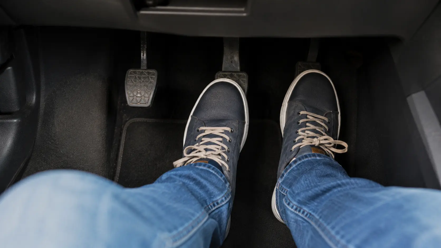 Pied droit sur l’accélérateur et pied gauche sur le frein dans une voiture immobile